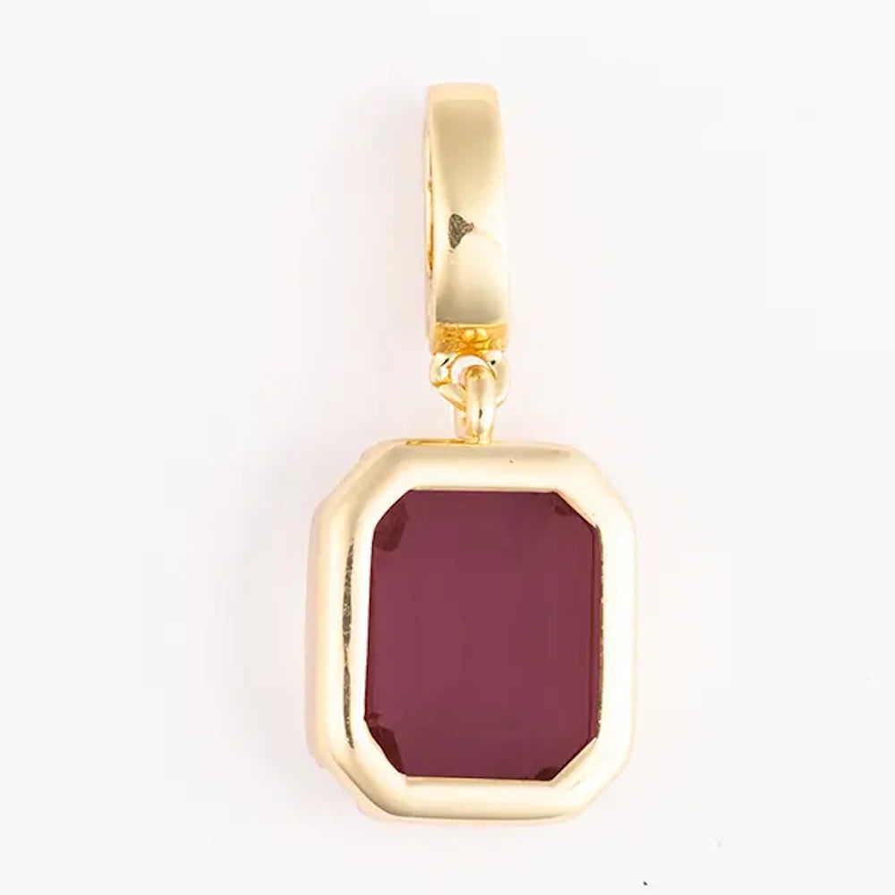 Gold pendant charm featuring an emerald-cut deep red gemstone set in a bezel frame.