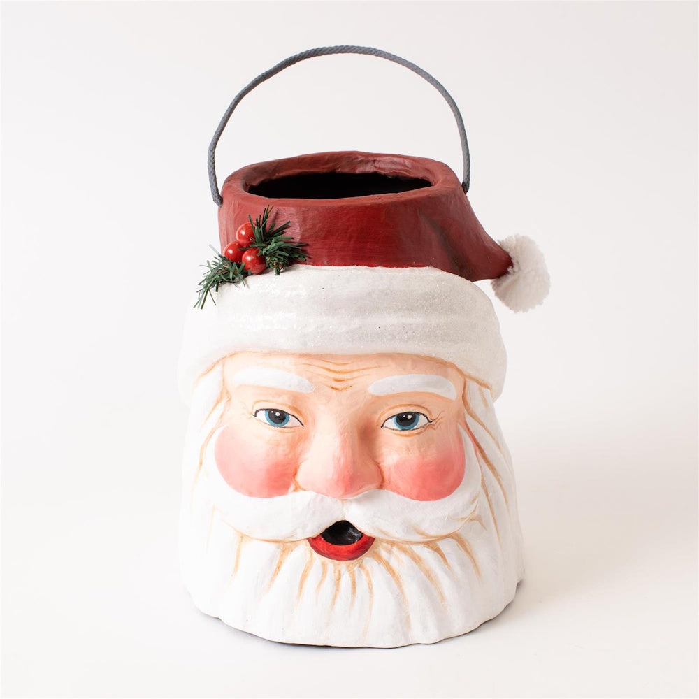 A festive Santa Claus head papier-mâché bucket container with a thin handle and a open top.
