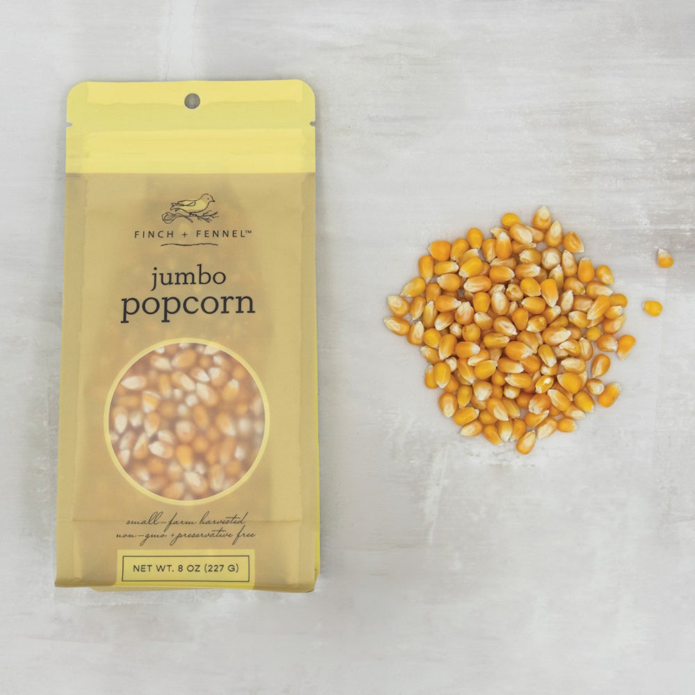A bag of Finch & Fennel jumbo popcorn kernels next to a pile of loose kernels, top-down view.