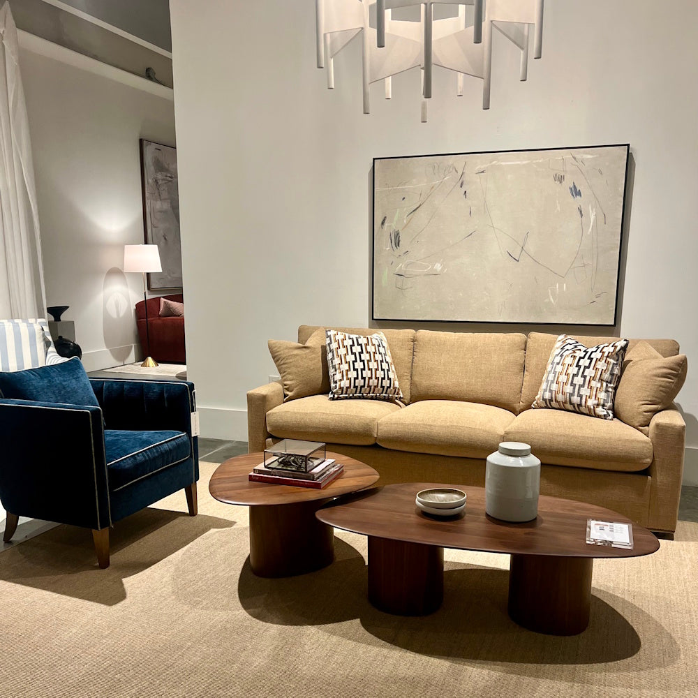Modern living room with a Kitt blue velvet accent chair, tan sofa, and nested wood coffee tables.