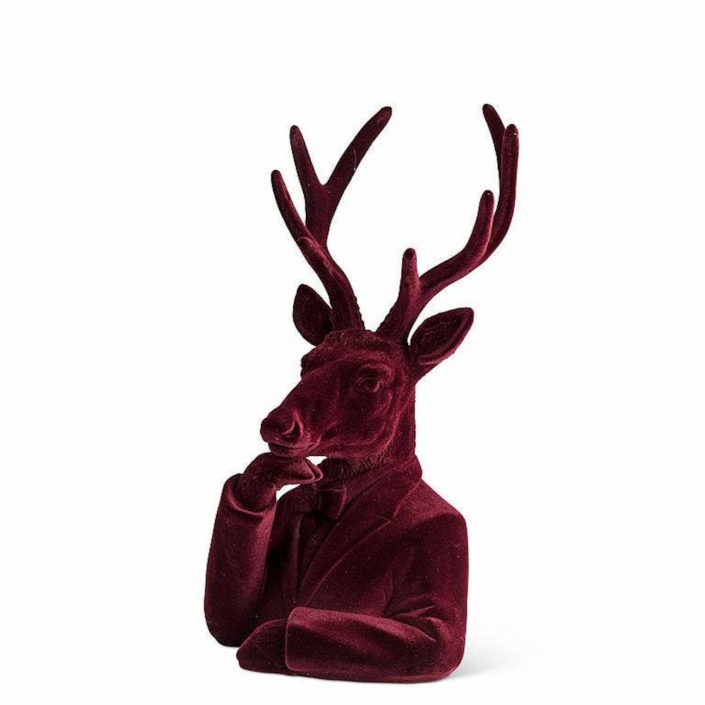 Velvet burgundy stag bust dressed in a suit, posing with one hand resting thoughtfully near its chin.