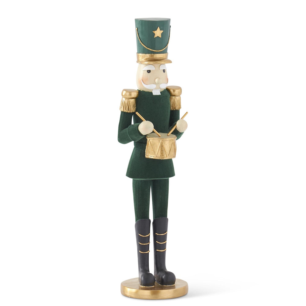 Side angle of a tall dark green velvet nutcracker figurine in a gold-trimmed uniform playing a drum.