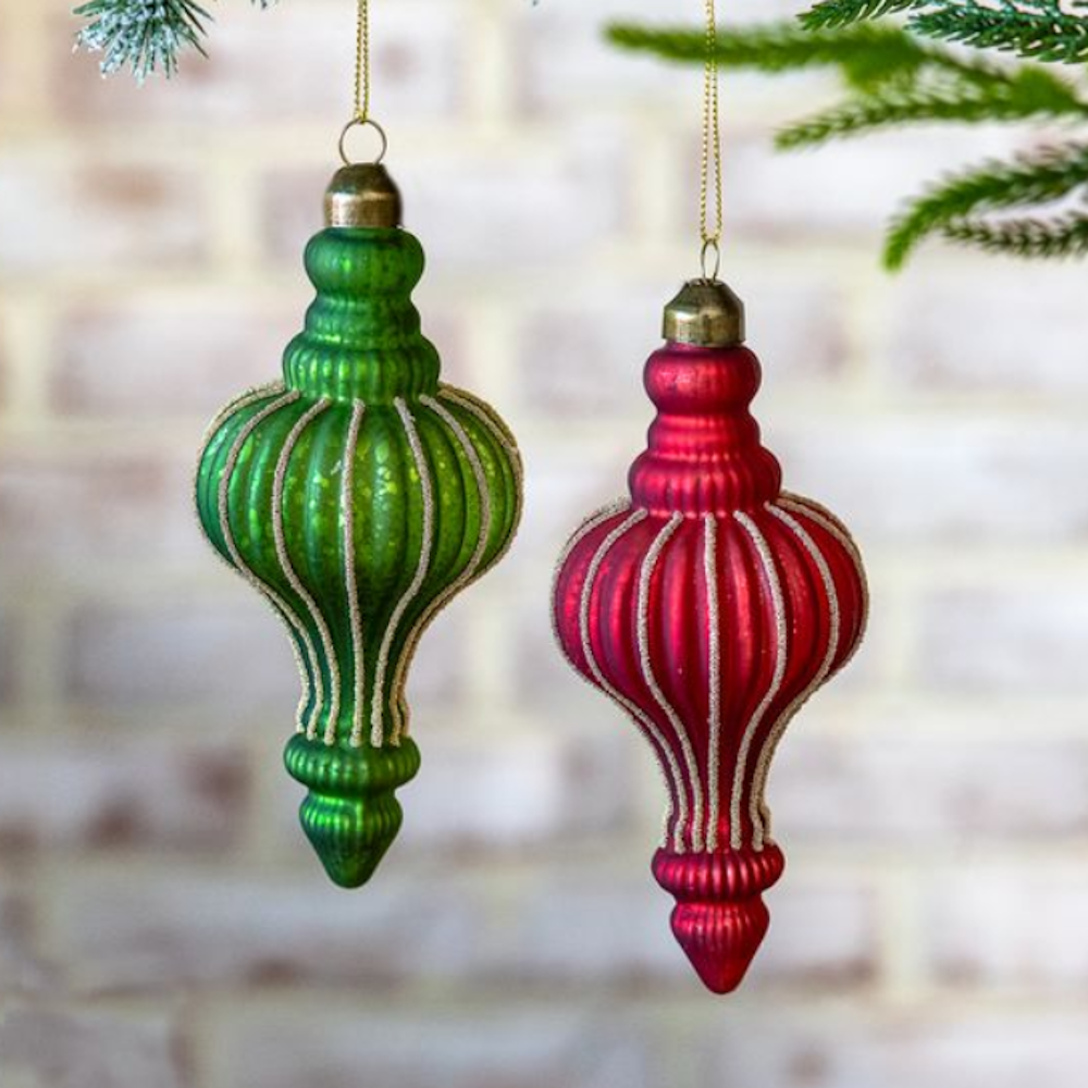 Large green and red ribbed glass finial ornaments with glitter details hanging on pine branches.