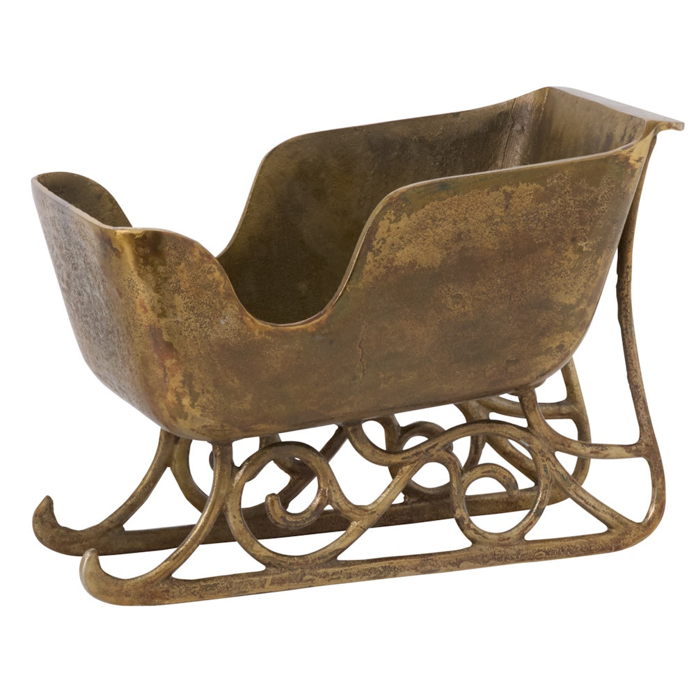 Vintage brass sleigh-shaped planter with ornate scrollwork runners.