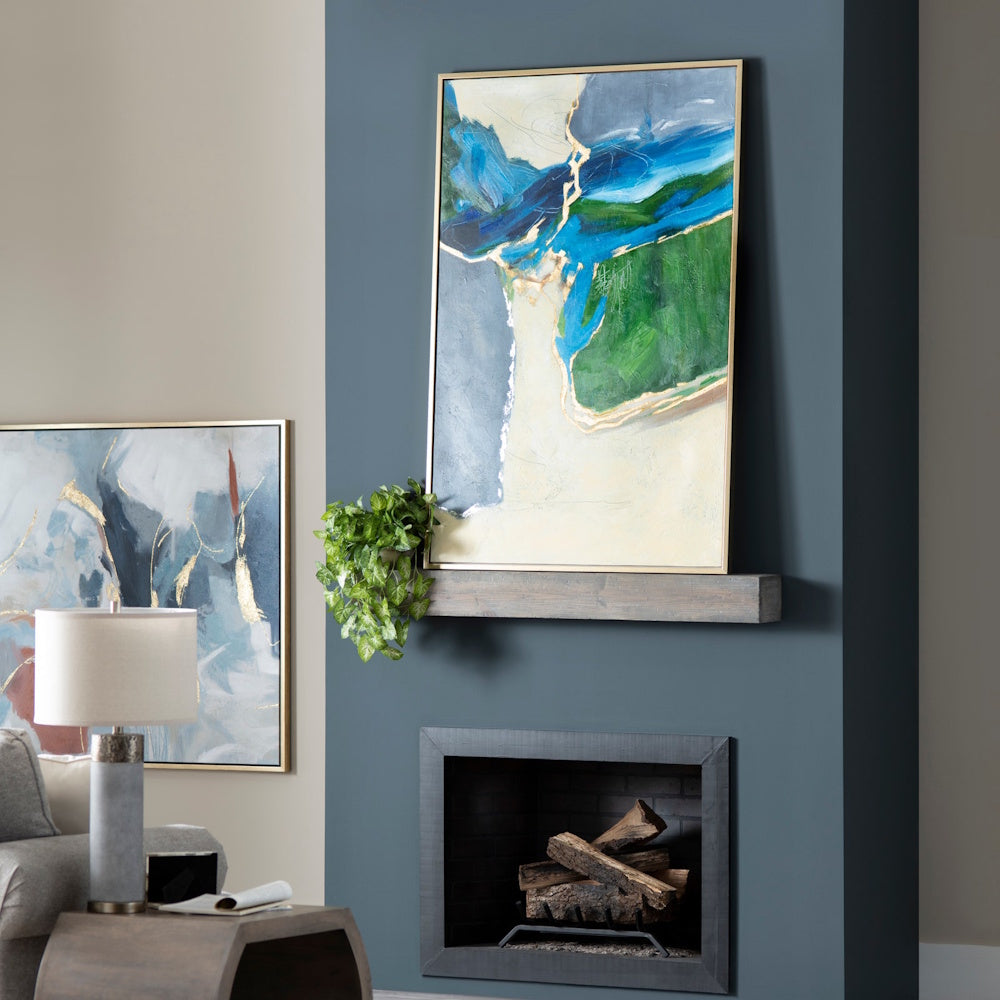 Abstract blue and green canvas art in a gold frame above a modern fireplace with a wood mantel and potted plant.