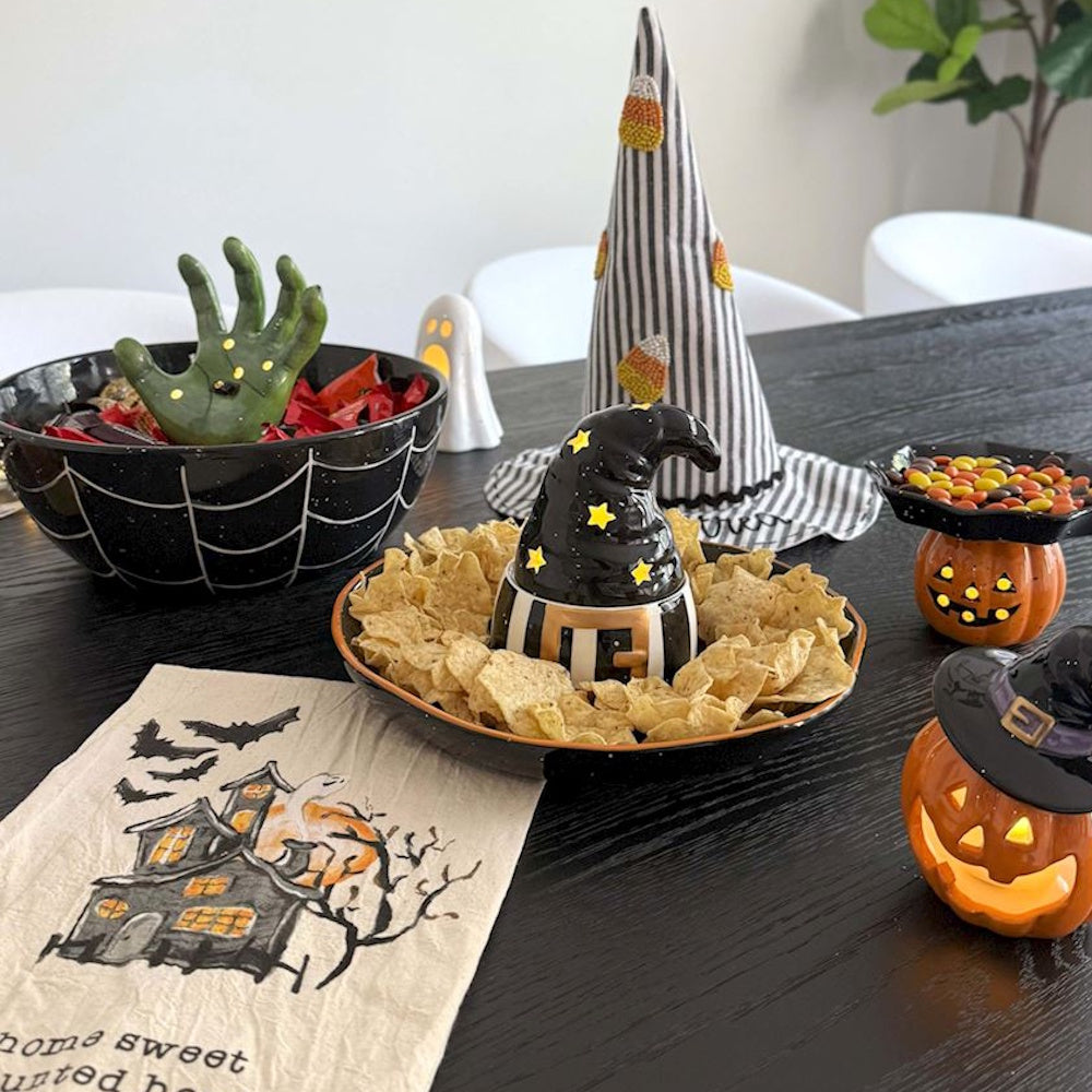 Ceramic witch hat chip and dip bowl platter surrounded by Halloween party decorations.
