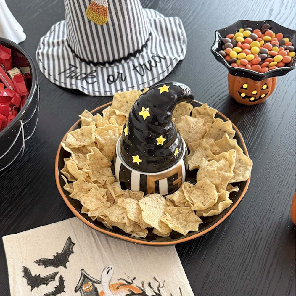 Halloween witch hat chip and dip platter surrounded by tortilla chips on a party table.