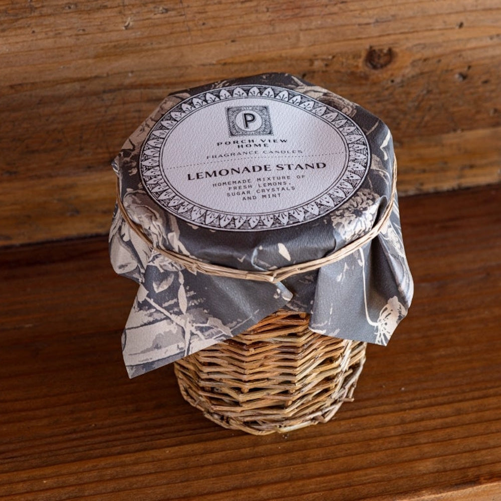 A Lemonade Stand scented candle in a woven wicker base with a decorative paper topper.