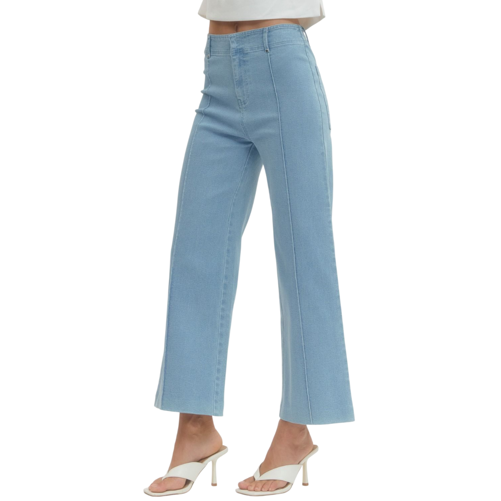 A person wearing light blue, high-rise, wide-leg pants with front seams and white heeled sandals.