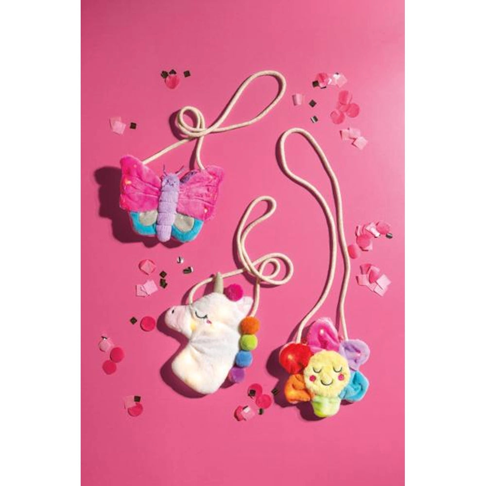 Three plush kids light up purses in butterfly, unicorn, and flower shapes on a vibrant pink background.
