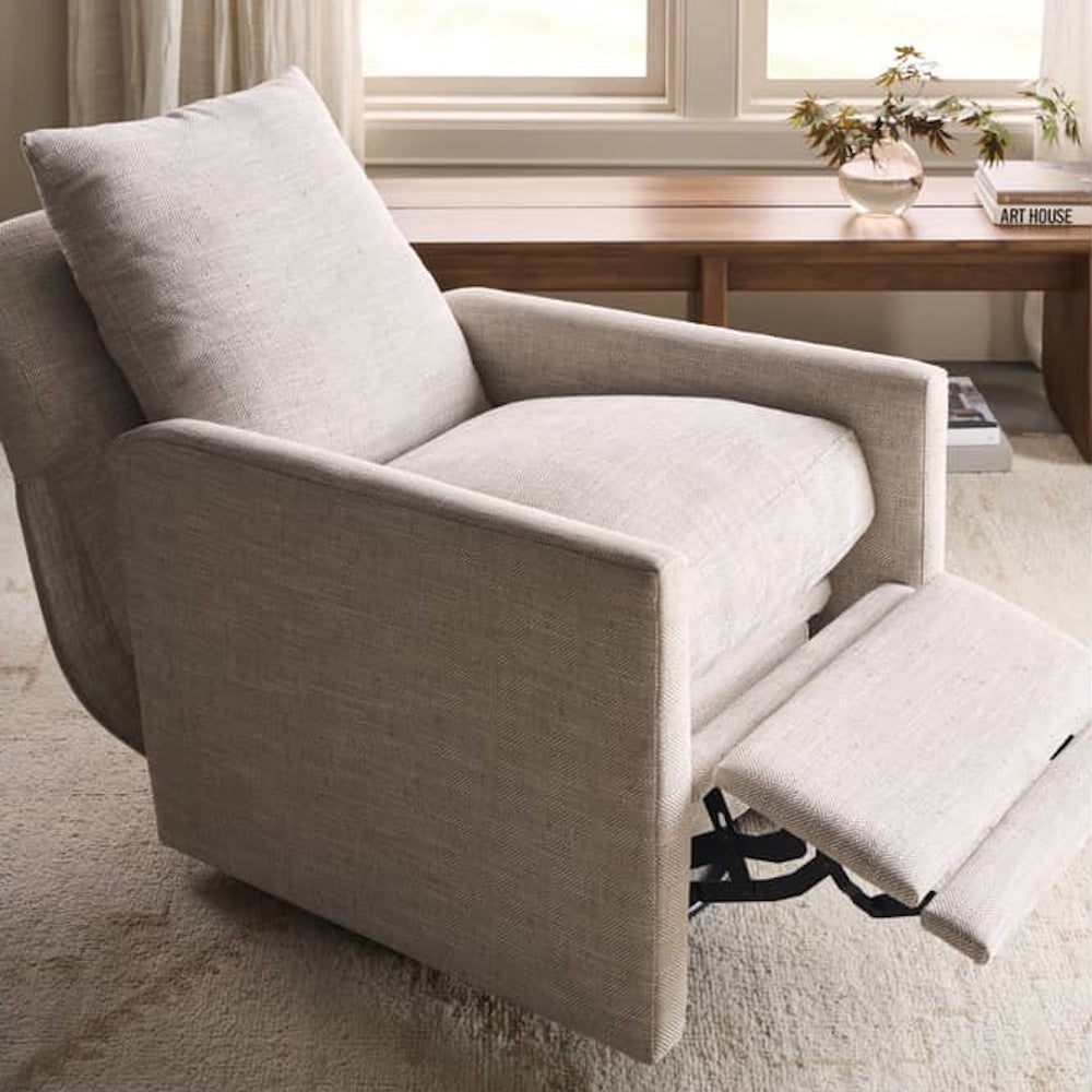 Beige upholstered recliner chair in a sunny living room with extended footrest and modern chevron pattern fabric.