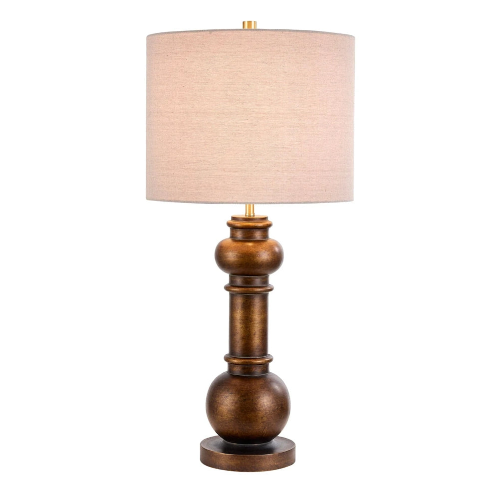 Classic bronze table lamp with a beige drum shade, featuring a sculpted pillar base for traditional home decor.