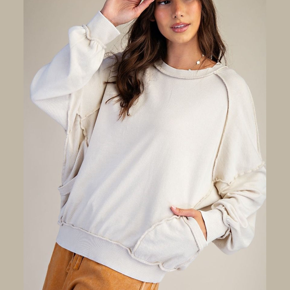 Woman wearing a cream mineral wash long-sleeve pullover with raw seam detailing and a relaxed fit.