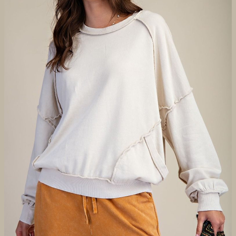 Cream long-sleeve mineral-washed pullover with cut-out seam detailing and a relaxed fit.