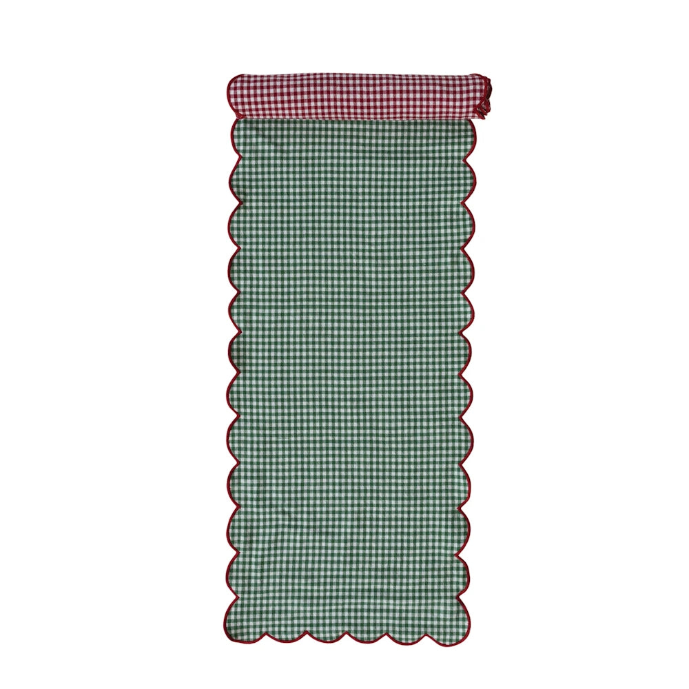 Reversible table runner with green gingham on top, red gingham rolled back, and red scalloped edges.
