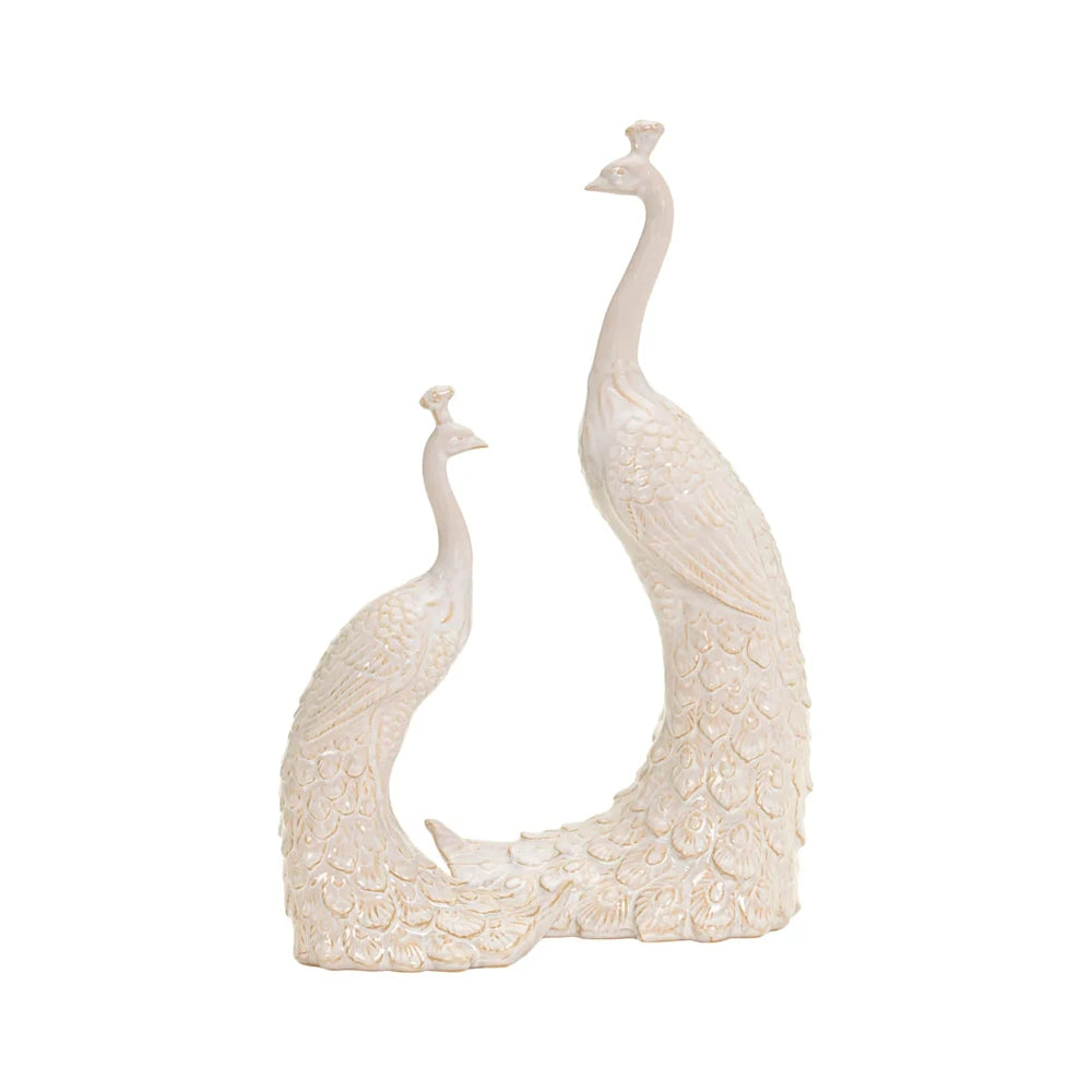 Two glossy, off-white ceramic peacock figurines, one taller than the other, featuring detailed feather patterns.