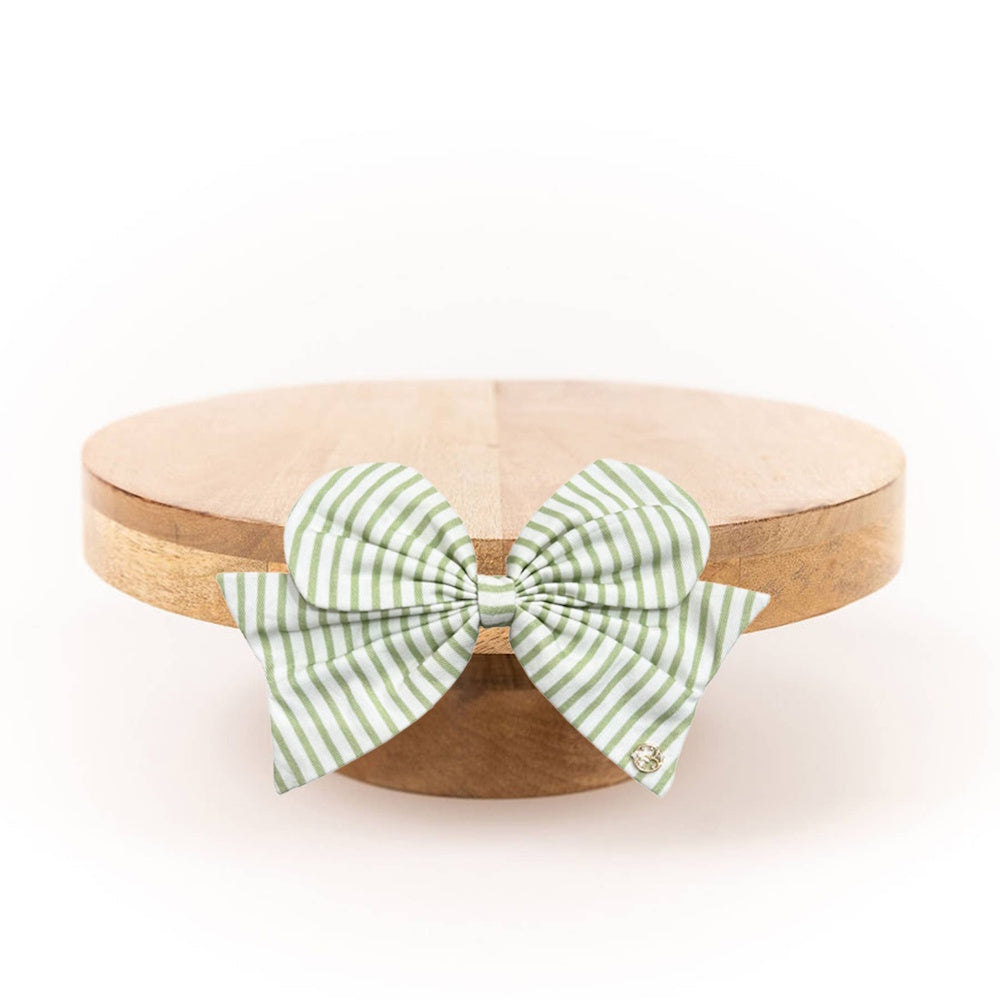 Wooden cake stand adorned with a green and white striped fabric bow on the front.