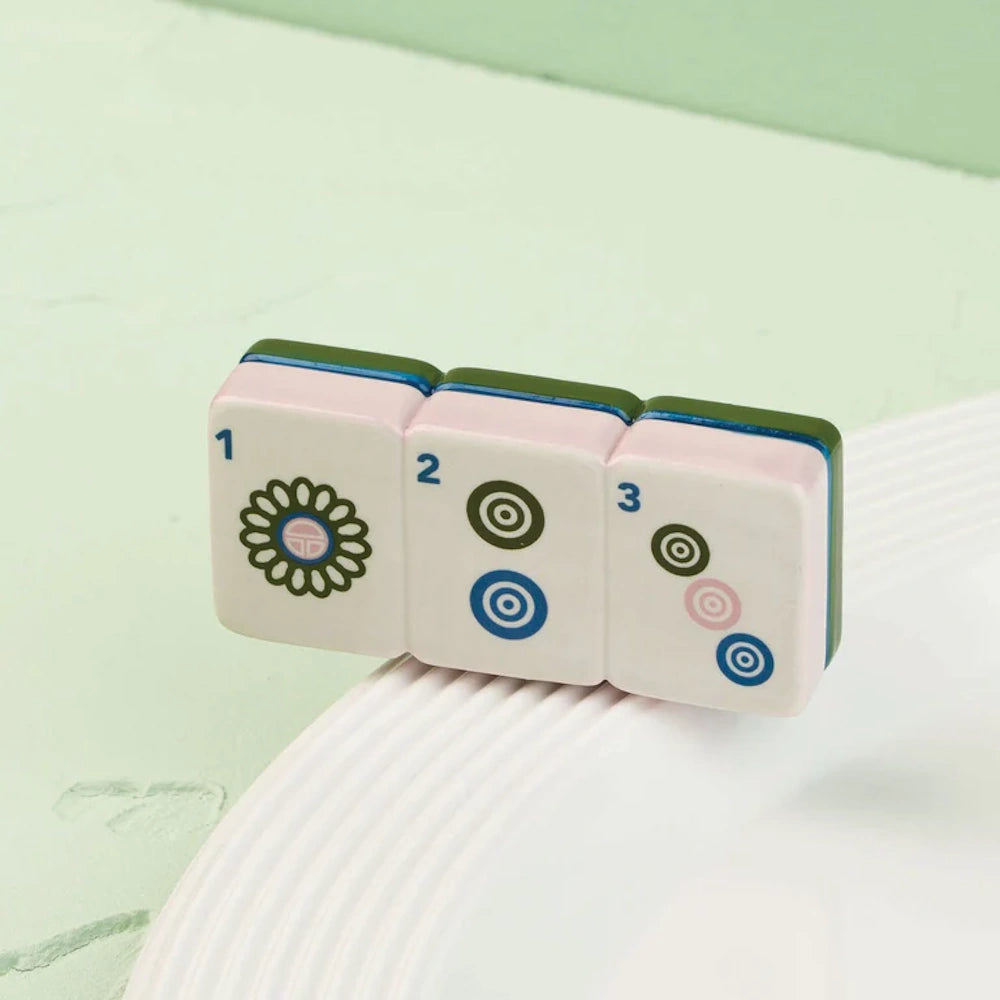Miniature ceramic row of three mahjong tiles numbered 1, 2, and 3 sitting on a white dish rim.