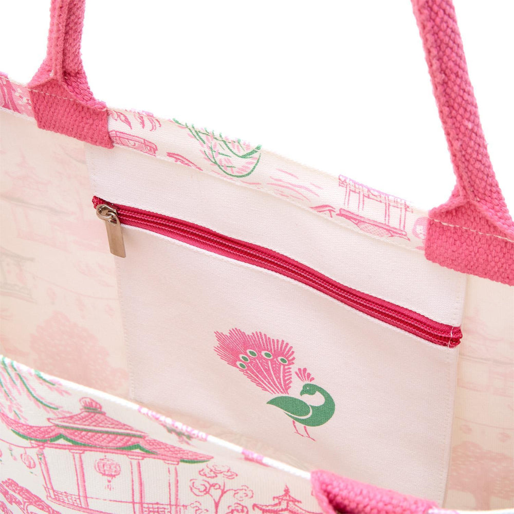 Inside view of the tote bag showing a zippered pocket with a pink and green peacock print.