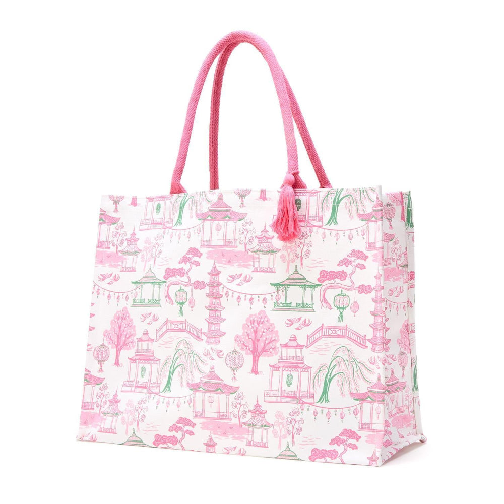 Pink and green block print tote bag featuring a pattern of pagodas and bridges with pink rope handles.