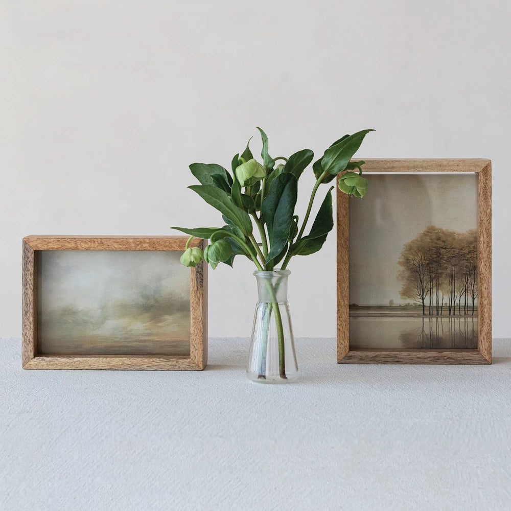 Mango wood floating glass photo frames with landscape art and green flowers in a glass vase on a white surface.