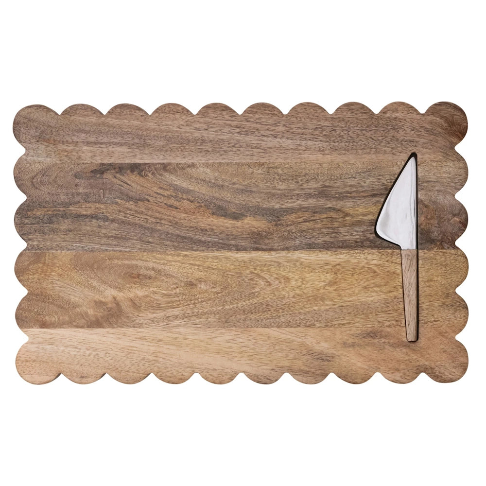 Scalloped edge wooden cheese board with inset stainless steel spreader knife on white background.