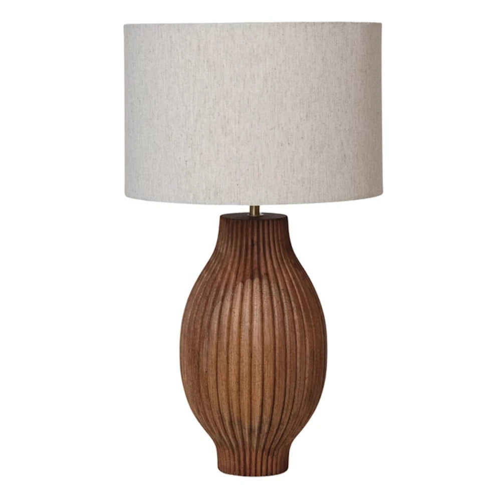Mango wood table lamp with vertical carved lines and a neutral fabric drum shade.   