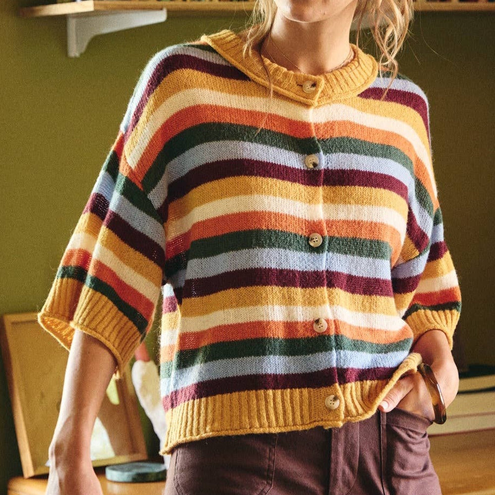 Woman wearing a short-sleeve button-down cardigan with colorful horizontal stripes.