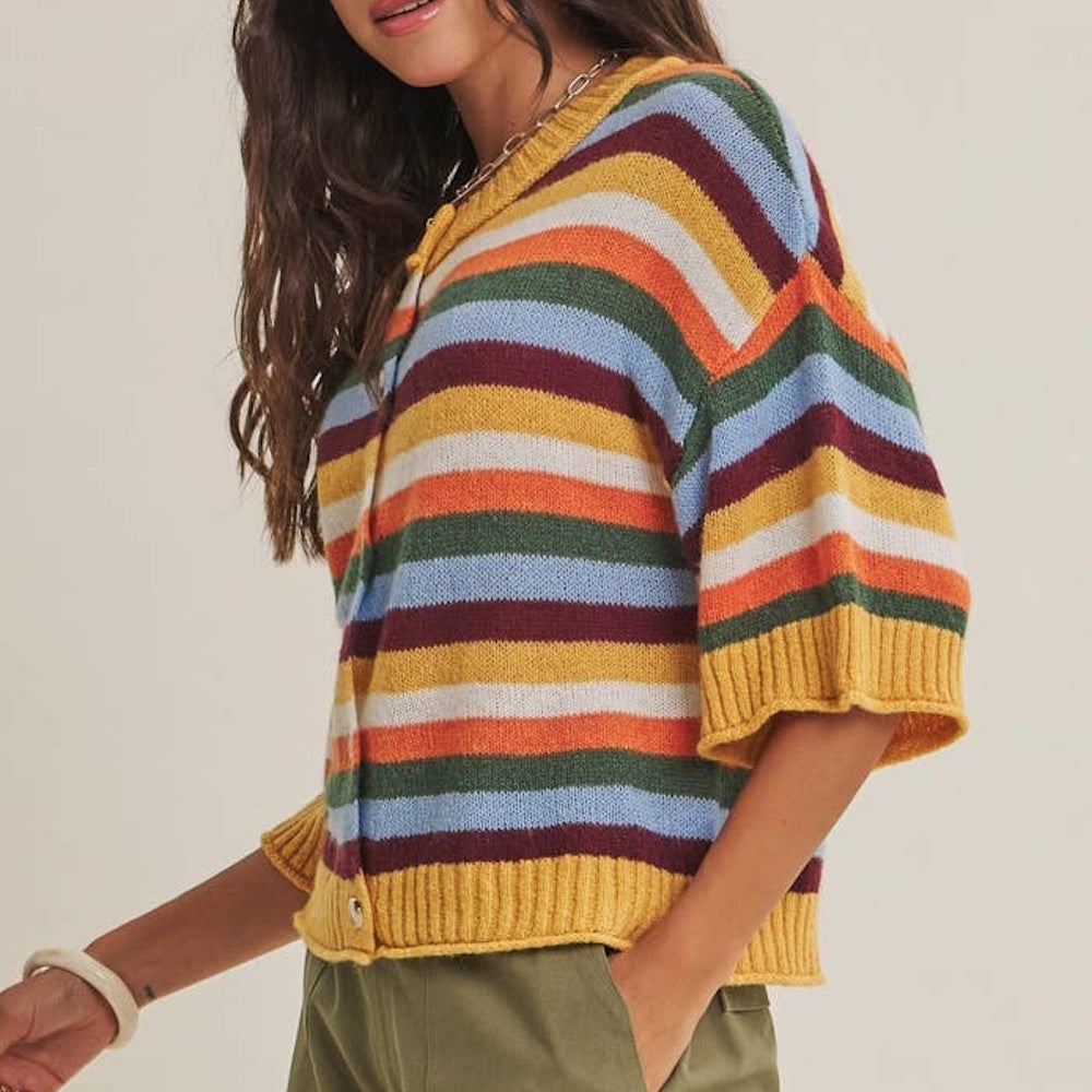 Side view of a short-sleeved, multicolor striped knit cardigan with ribbed trim paired with olive pants.