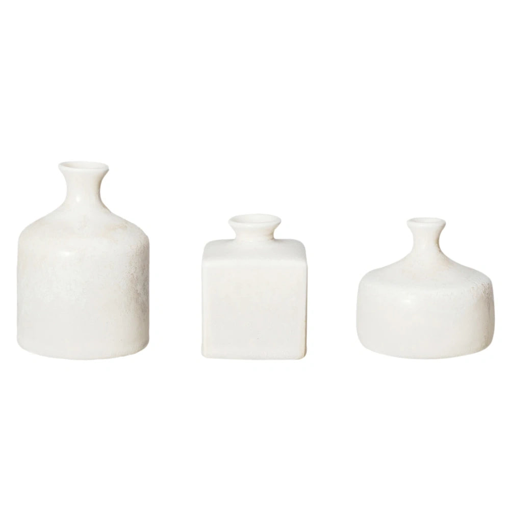 Set of three small textured white ceramic vases in varied geometric shapes lined up against a plain white background.
