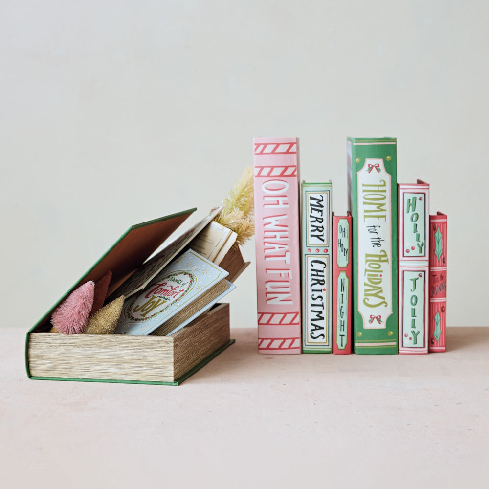 Festive holiday book-shaped storage boxes displayed upright and open with small decor inside.