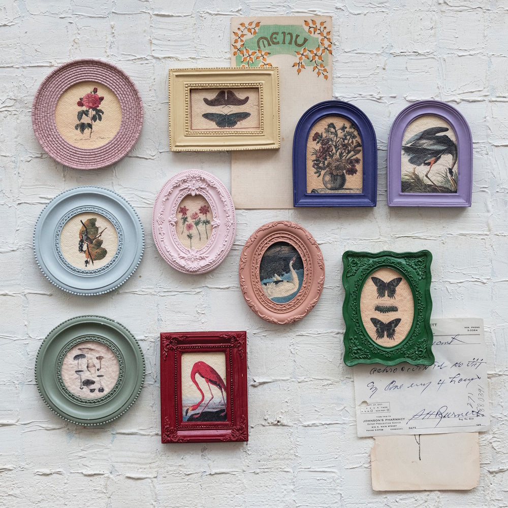 Assorted mini framed art magnets with botanical, floral, and bird prints on a white brick wall.