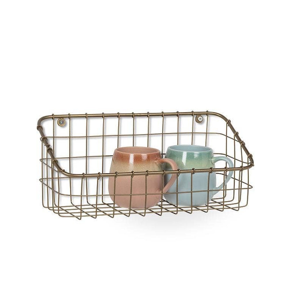 Brass wire wall-mounted storage basket holding two ceramic coffee mugs.