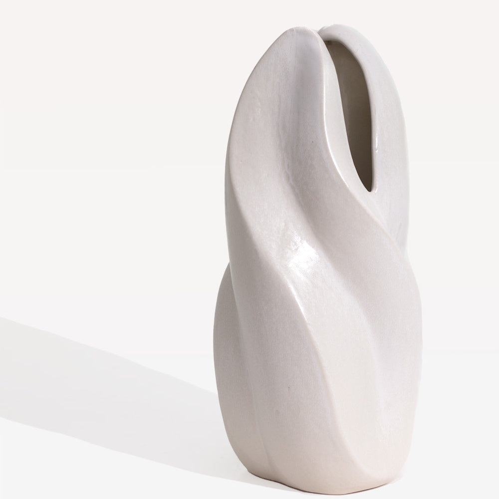 Tall, off-white ceramic Merlin vase with a modern, twisted organic shape and a smooth matte finish on a white background.