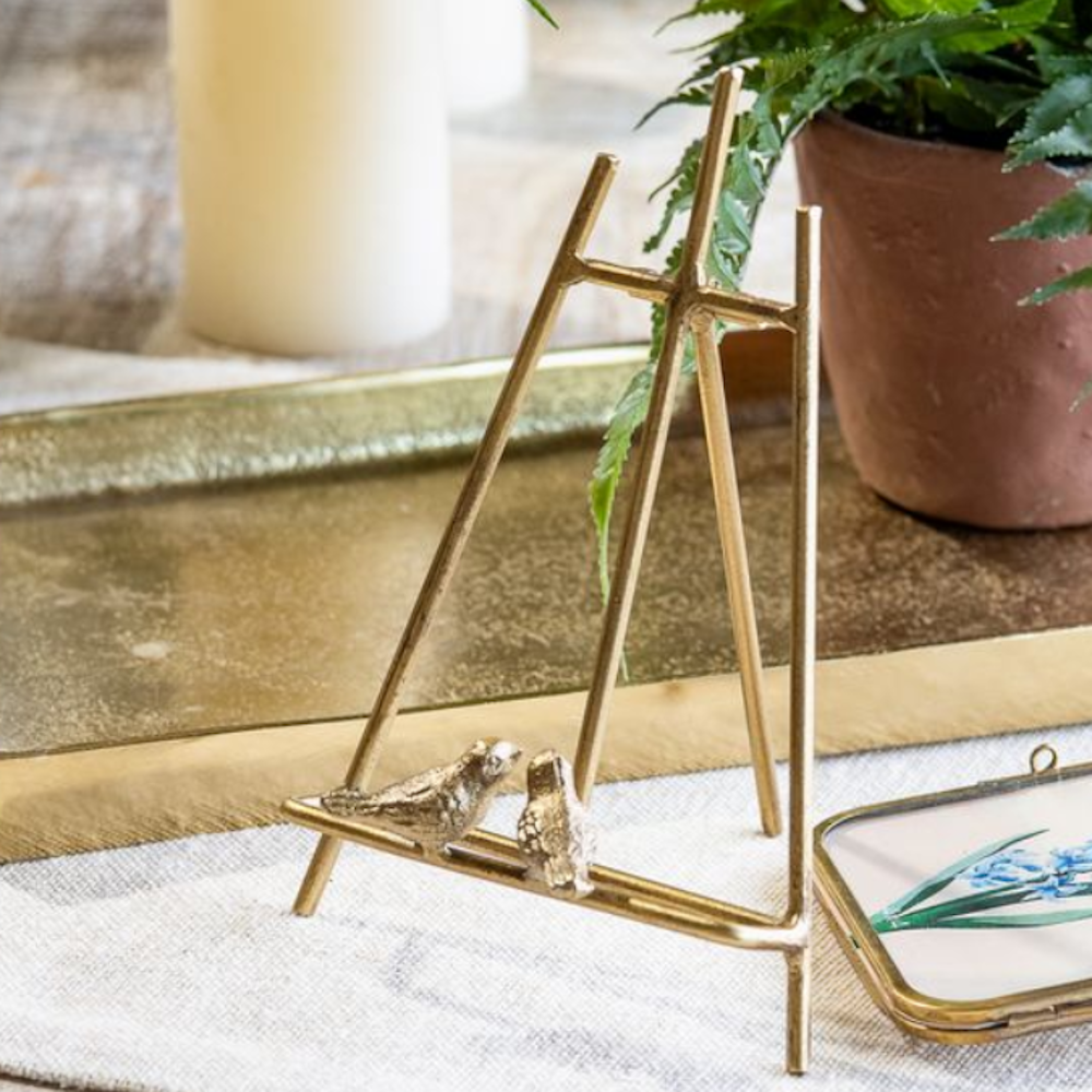 Small gold tabletop easel decorated with two miniature bird figures on the front ledge.