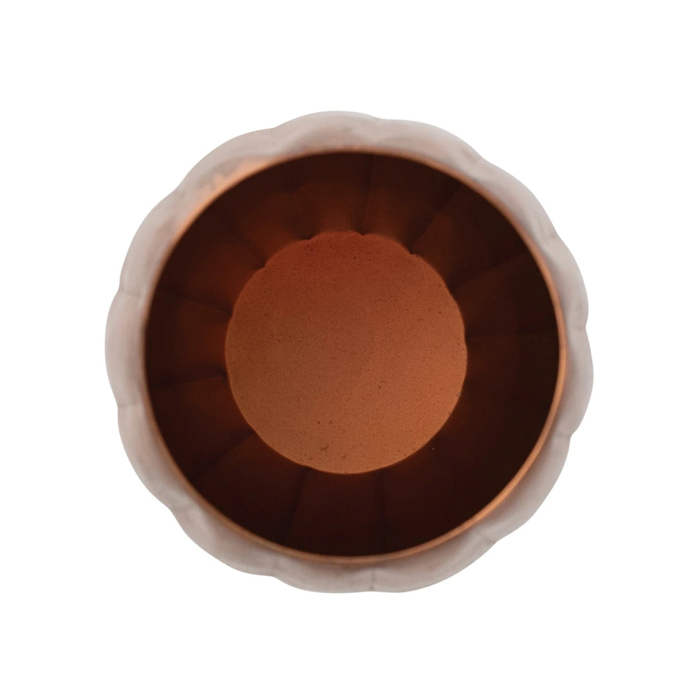 Top-down view inside the hollow bronze metal jack-o'-lantern candle holder showing its ribbed interior.