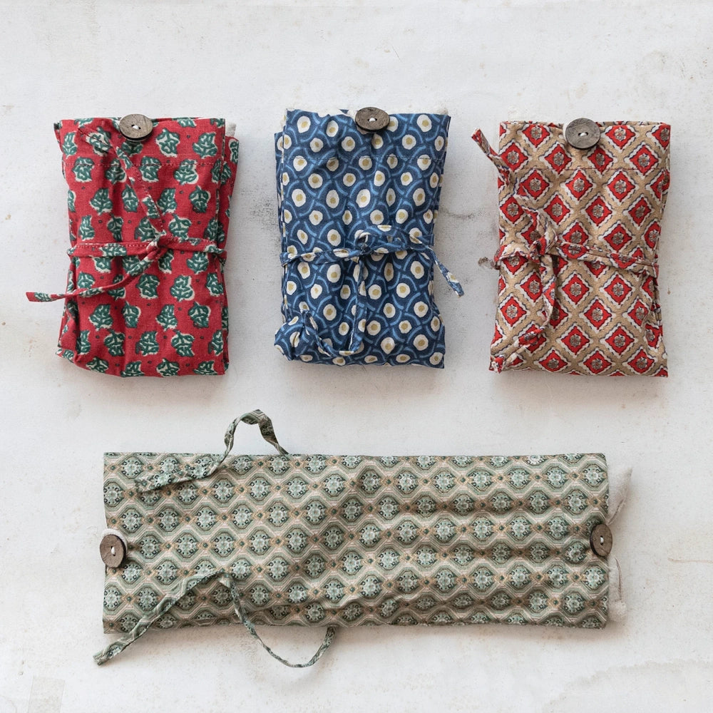 Four patterned microwaveable hot and cold packs with lentil and lavender filling, featuring wooden buttons and ties.