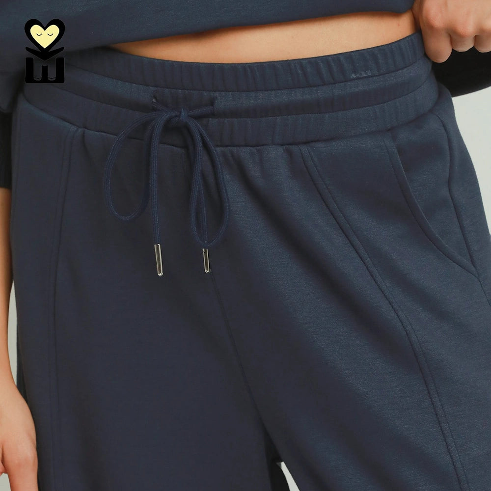 Close-up of midnight blue knit pants with a drawstring waist, metal aglets, and front seams.