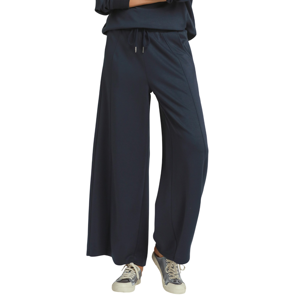 Front view of a woman wearing midnight blue wide-leg pants with a drawstring waistband and sneakers.