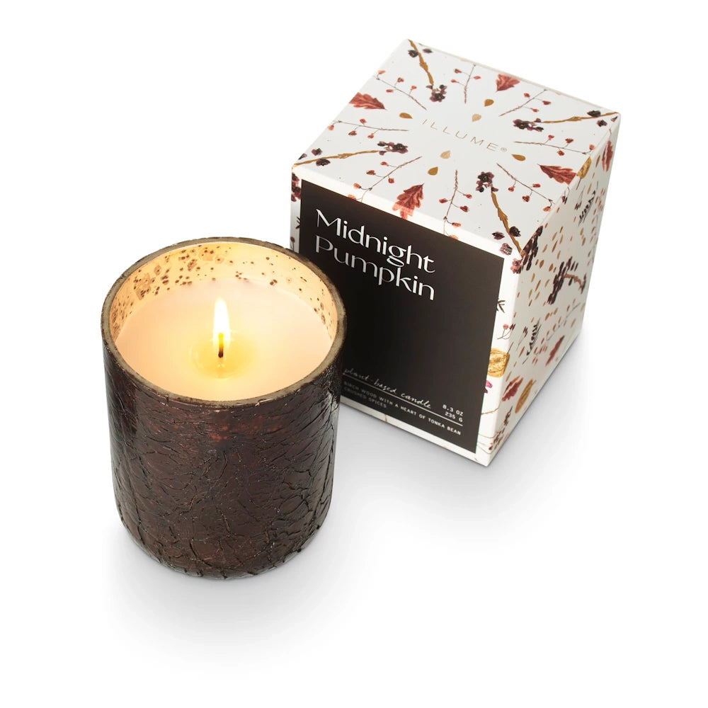Lit Midnight Pumpkin candle in a dark crackle glass jar next to its decorative floral packaging box.