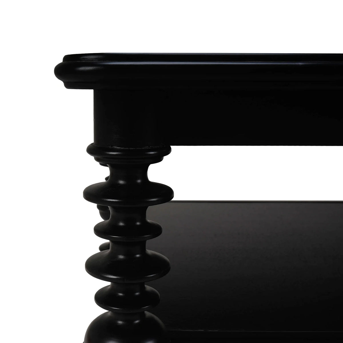 Close-up of a black wooden coffee table featuring a detailed spool turned leg and a lower shelf.