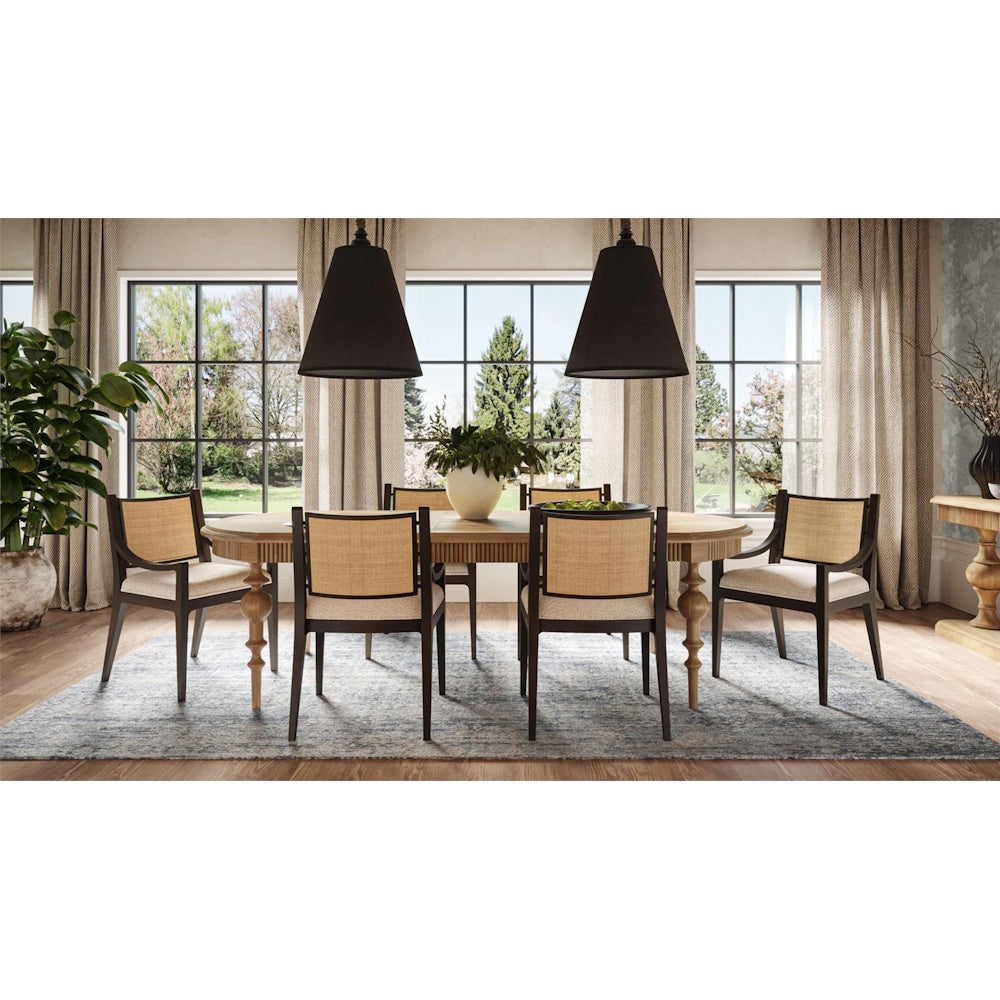 Modern dining room setup with rattan back upholstered chairs around a wood table.