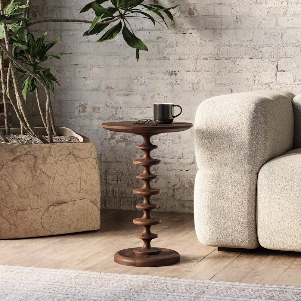 Milano round side table in walnut with a ribbed pedestal base next to a modern sofa in a living room.