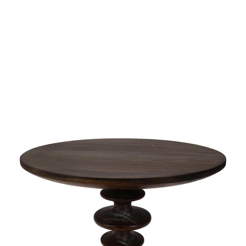 Close up of a Milano round side table showing the dark wood grain tabletop surface and carved pedestal base.