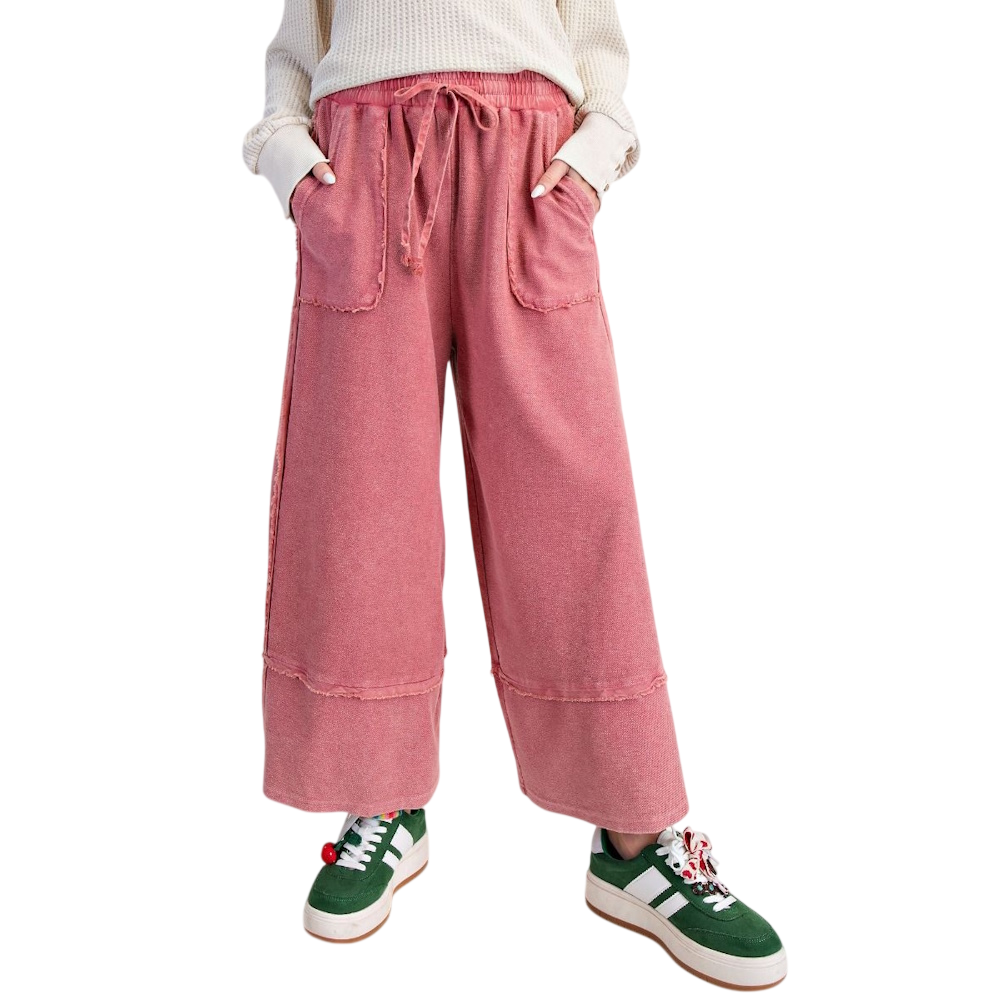 Pink mineral-wash palazzo pants with a drawstring waist, raw-edge pockets, and a wide-leg cropped fit.