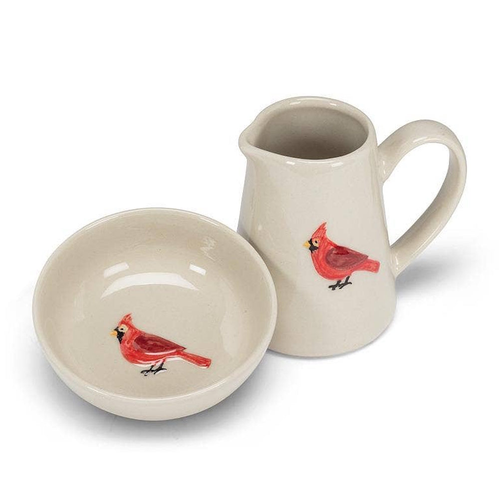 Cream ceramic mini creamer pitcher and matching shallow dish, each featuring a painted red cardinal.
