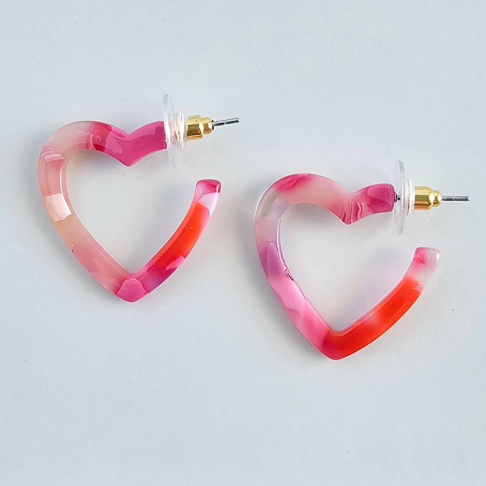 Pink marbled resin heart-shaped hoop earrings with gold posts on a white background.
