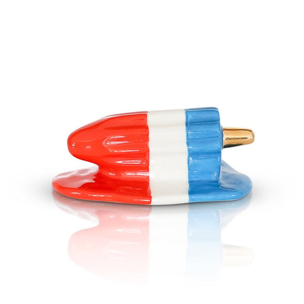 A melting red, white, and blue rocket popsicle ceramic sculpture with a gold stick on a white background.