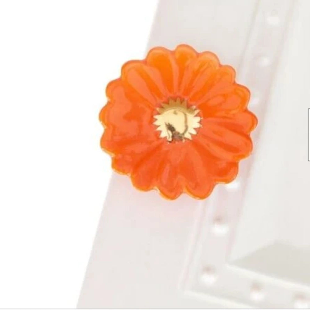 Mini bright orange gerbera daisy ceramic attachment with a metallic center.