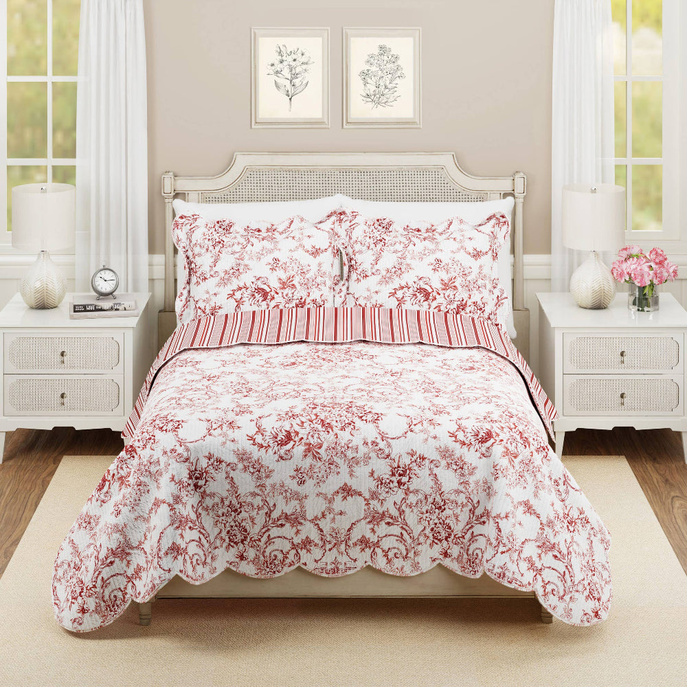 Red garden toile quilt set with scalloped edges and striped accents on a classic bed with white nightstands and lamps.